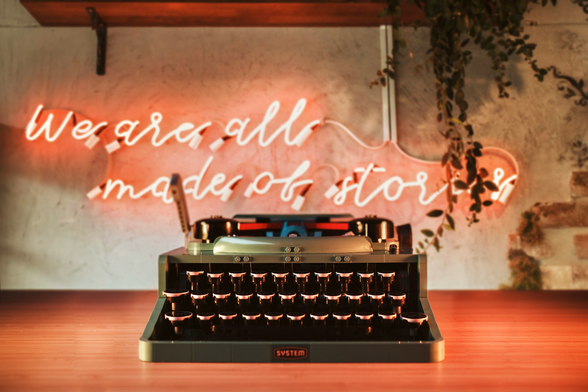 Old-fashioned typewriter in front of a red neon sign with the words "We are all made of stories".